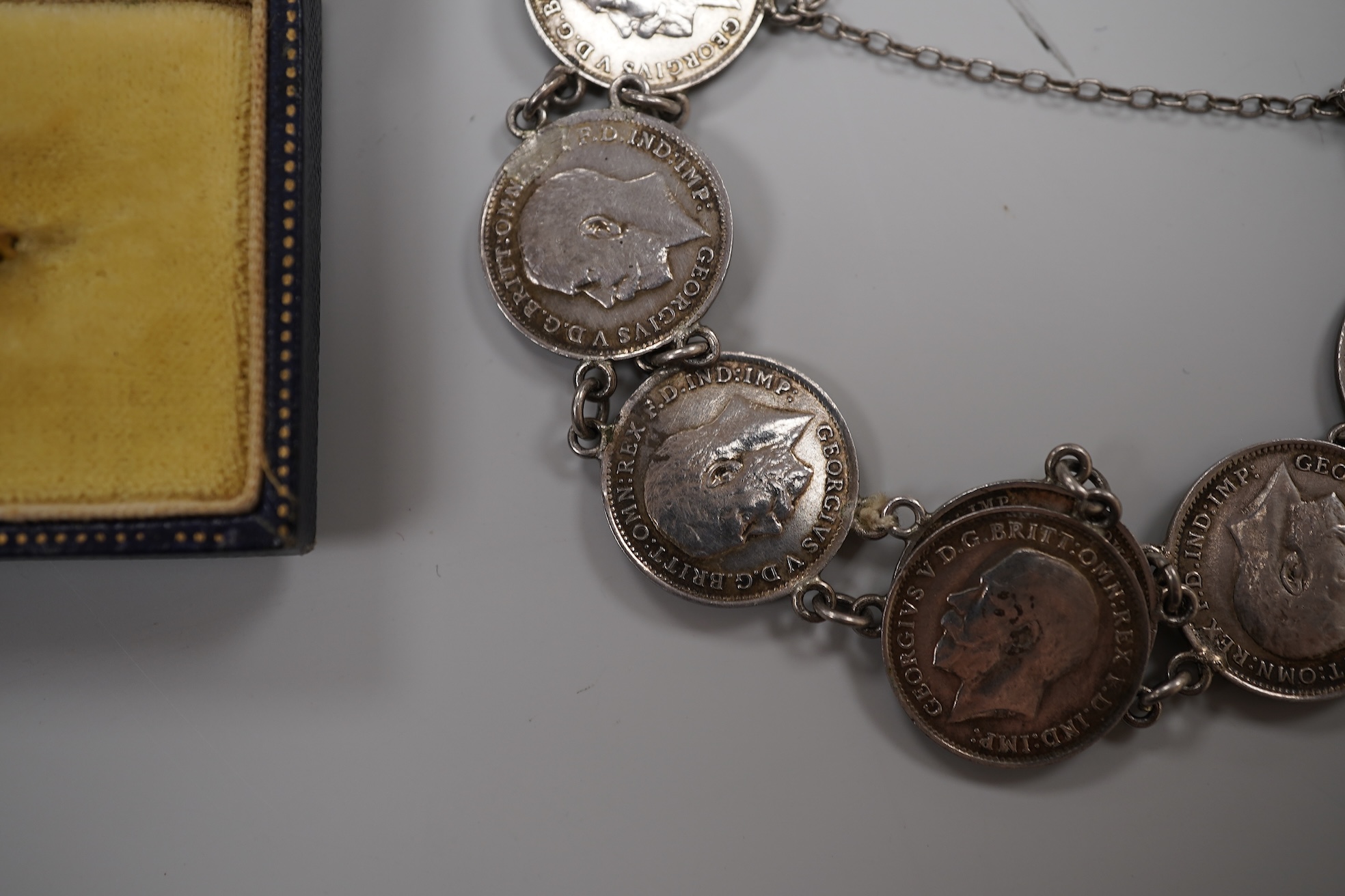 A cased early 20th century 9ct and single stone split pearl set bar brooch, 42mm and a white metal coin bracelet.